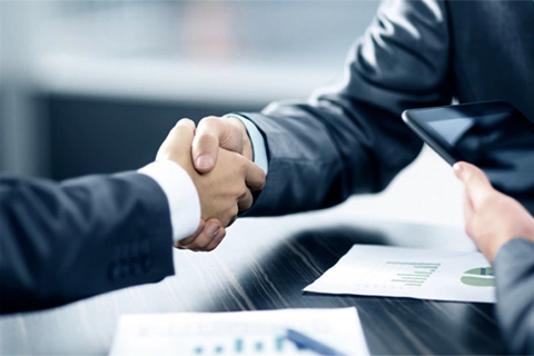 Photo of two people shaking hands over a desk